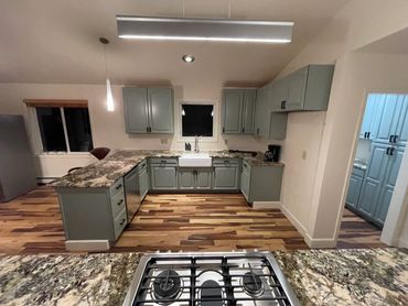 Modern kitchen with green cabinets and granite countertops.