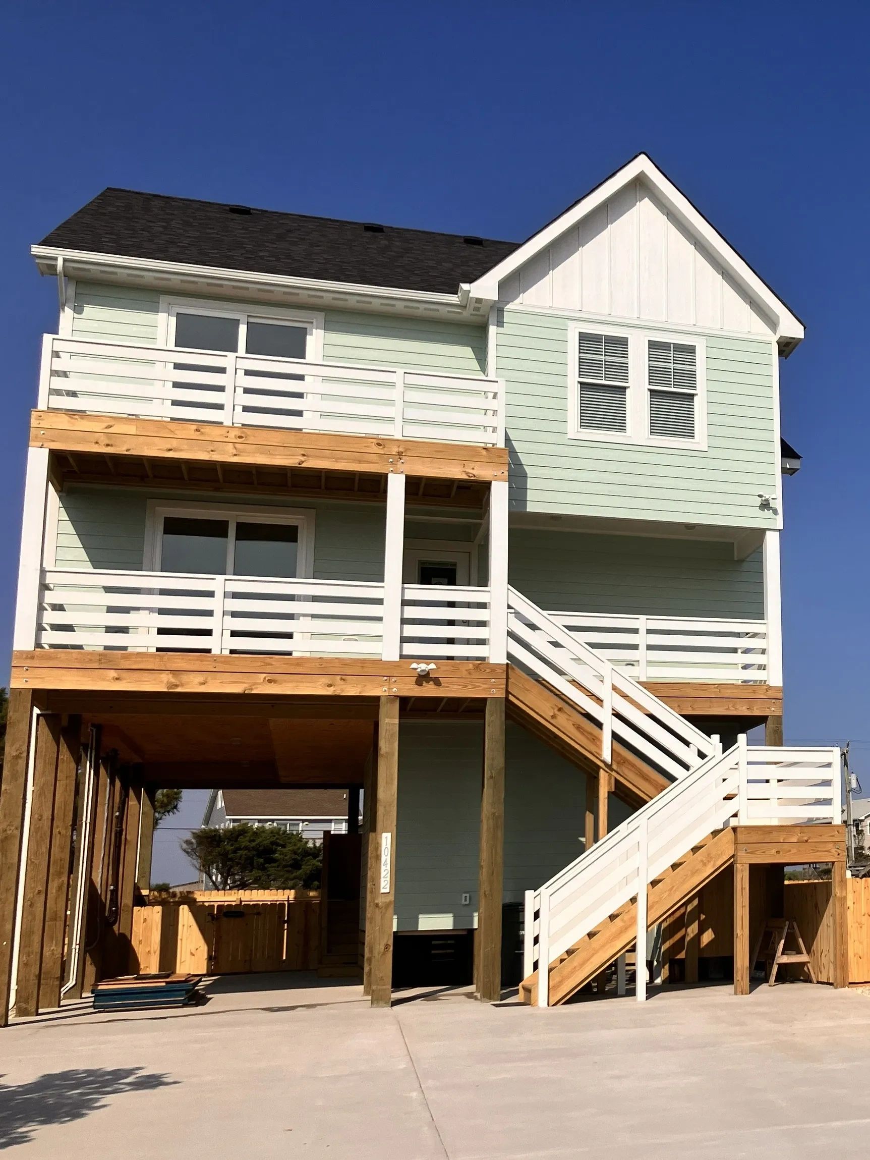 Modern two-story house with wooden stairs and white railings.