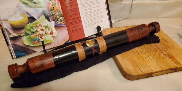 A bottle of wine with wooden holders on a kitchen counter.