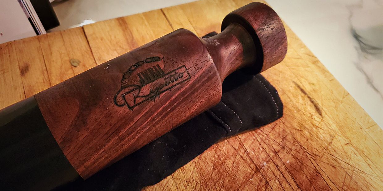 Wooden handled pepper grinder on a cutting board.