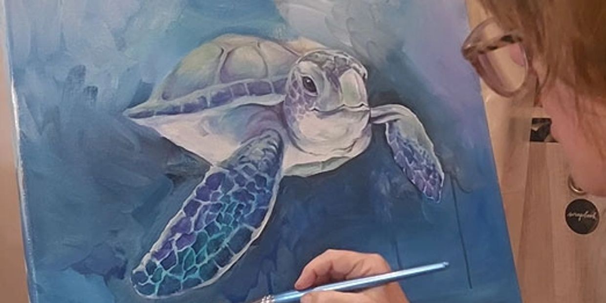Artist painting a sea turtle on canvas.
