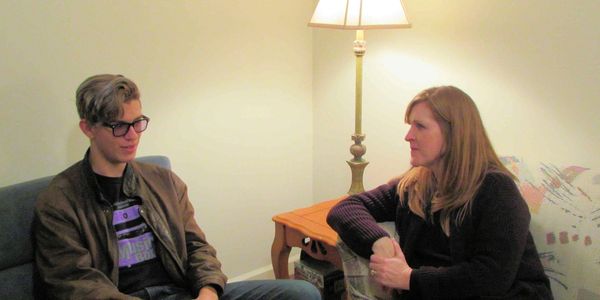 A young man and woman engaged in a serious conversation in a cozy room.