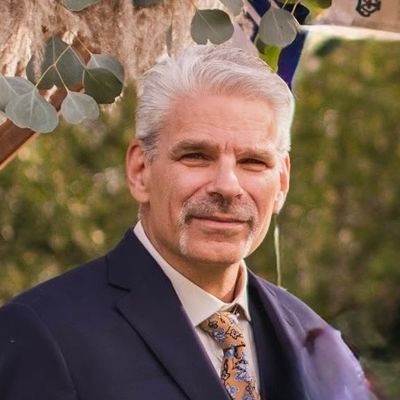 Portrait of a distinguished older man in a suit outdoors.