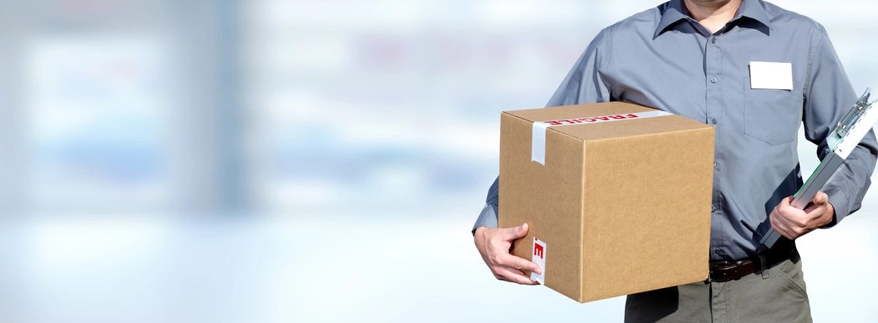 Delivery person holding a package and clipboard, ready for shipment.