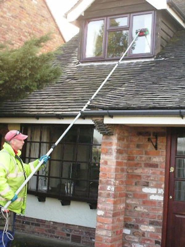 window cleaning using a pole to reach over a sloping roof.