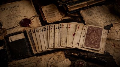 Vintage playing cards and old documents arranged on a dark surface.