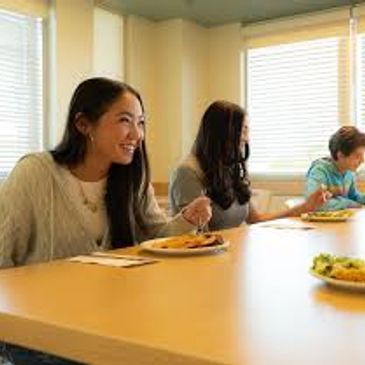 Three people sitting at a table eating a meal.