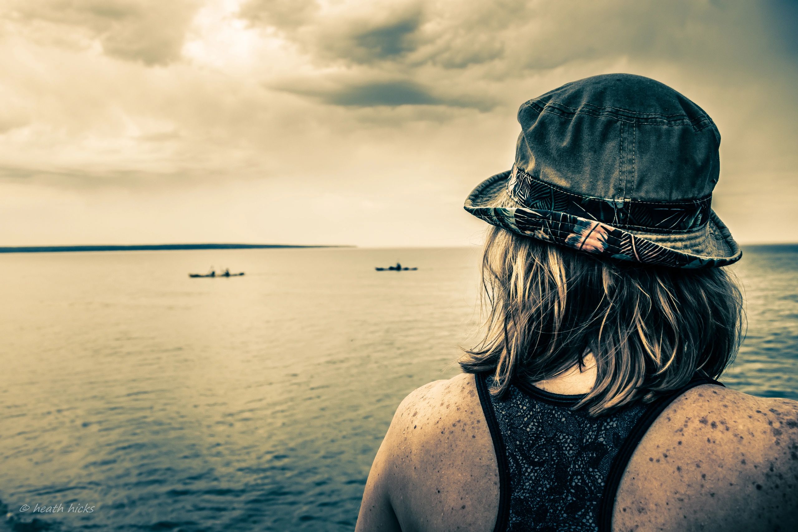 Woman staring into the horizon, lake superior, kayaks, cloudy day.