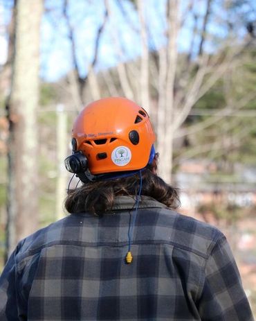 Person wearing an orange helmet and plaid jacket outdoors.