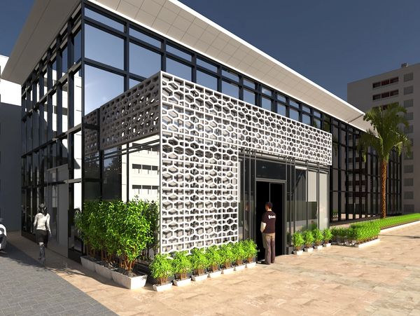 Modern building entrance with geometric facade and greenery.