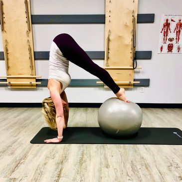 Pilates mat balancing exercise with large stability ball
