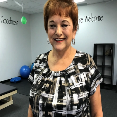 Smiling woman in a patterned blouse stands in a decorated room.