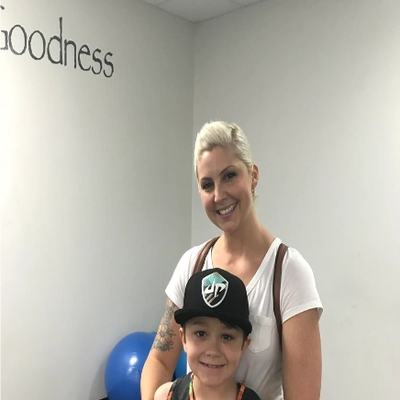 Smiling woman hugs young boy wearing a cap in a fitness room.