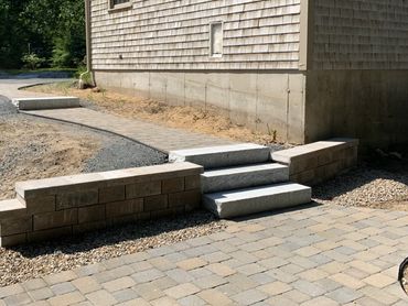 Custom retaining wall built for granite steps leading to a custom brick pathway.