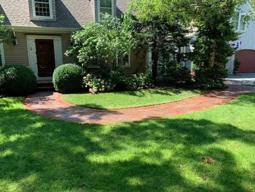 Elegant entrance to a home with a brick pathway weaving through a lush garden.