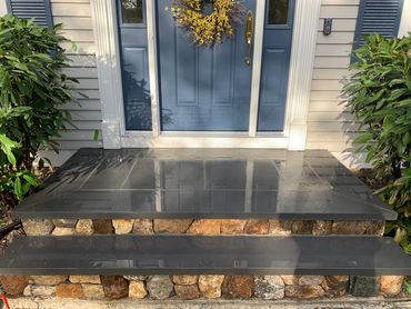 Blue stone and natural stone veneer steps to entrance of cape cod home.