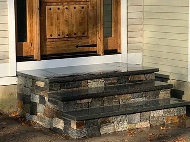 Historic cape cod home restored with stone veneer steps.