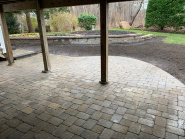 Patio built under a raised deck, with stone pavers, comfortable seating for a cozy outdoor retreat.