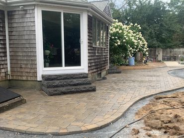 Granite steps lead to patio with elegant pavers wrapping around the back patio to a custom walkway.