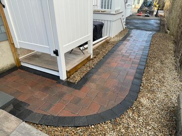 Outdoor shower pathway to the home entrance. Paver brick with frame and stone surrounding.