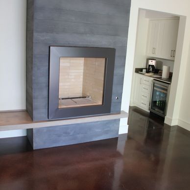 concrete fireplace and countertops in modern home with stained concrete floors