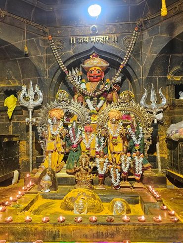Decorated Hindu temple altar with lit oil lamps and colorful rangoli.