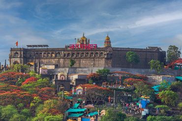 Historic fort atop a hill with colorful trees and visitors below.