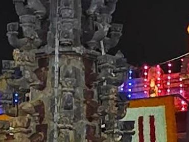Illuminated temple complex at night with visitors and ornate architecture.