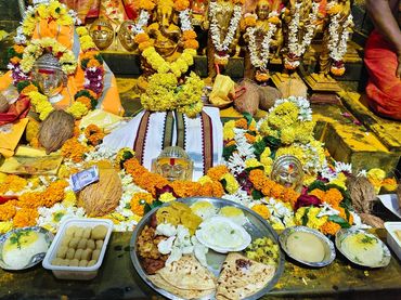 Hindu deities adorned with flowers and offerings at a temple.