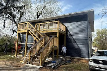 Newly built two-story house with wooden stairs and blue siding.