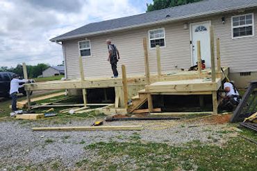 Construction of a wooden deck on a house with workers actively building it.