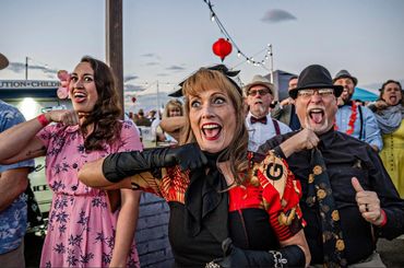A lively group of people making funny faces and gestures at an outdoor event.