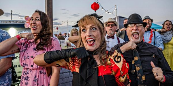A lively group of people making funny faces and gestures at an outdoor event.