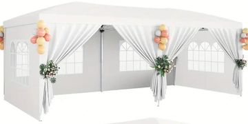 White party tent decorated with balloons and flowers on curtains.