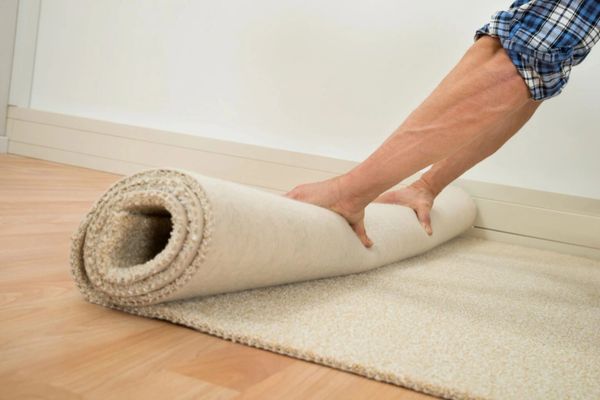 Person unrolling new beige carpet.