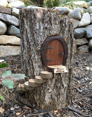 A tiny wooden door on a tree stump labeled 'Boo's Hideaway' with small log steps.