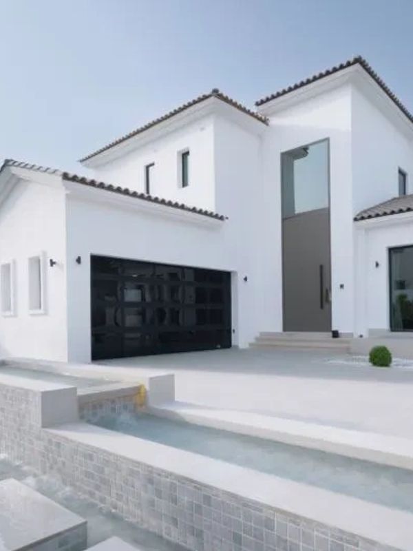 Exterior of white home with black garage and black roof.