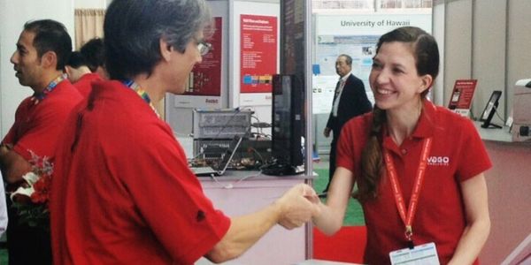 Friendly PTM staffer greeting a trade show booth visitor.