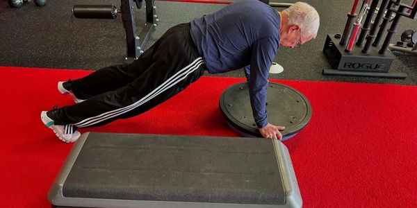 Older man doing push-ups on a Bosu ball.