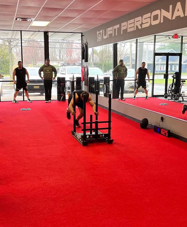 Athlete pushing a weighted sled in a fitness studio.