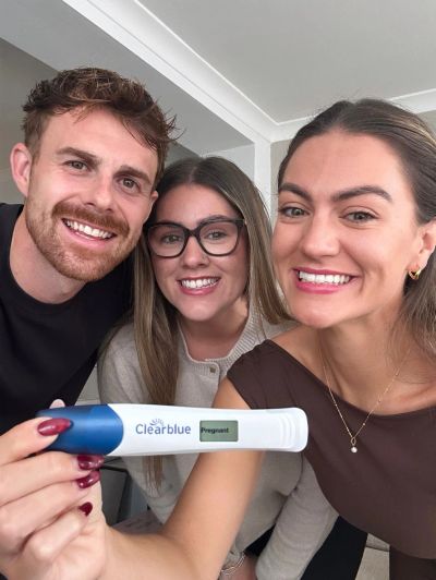 Three friends happily show a positive pregnancy test result.