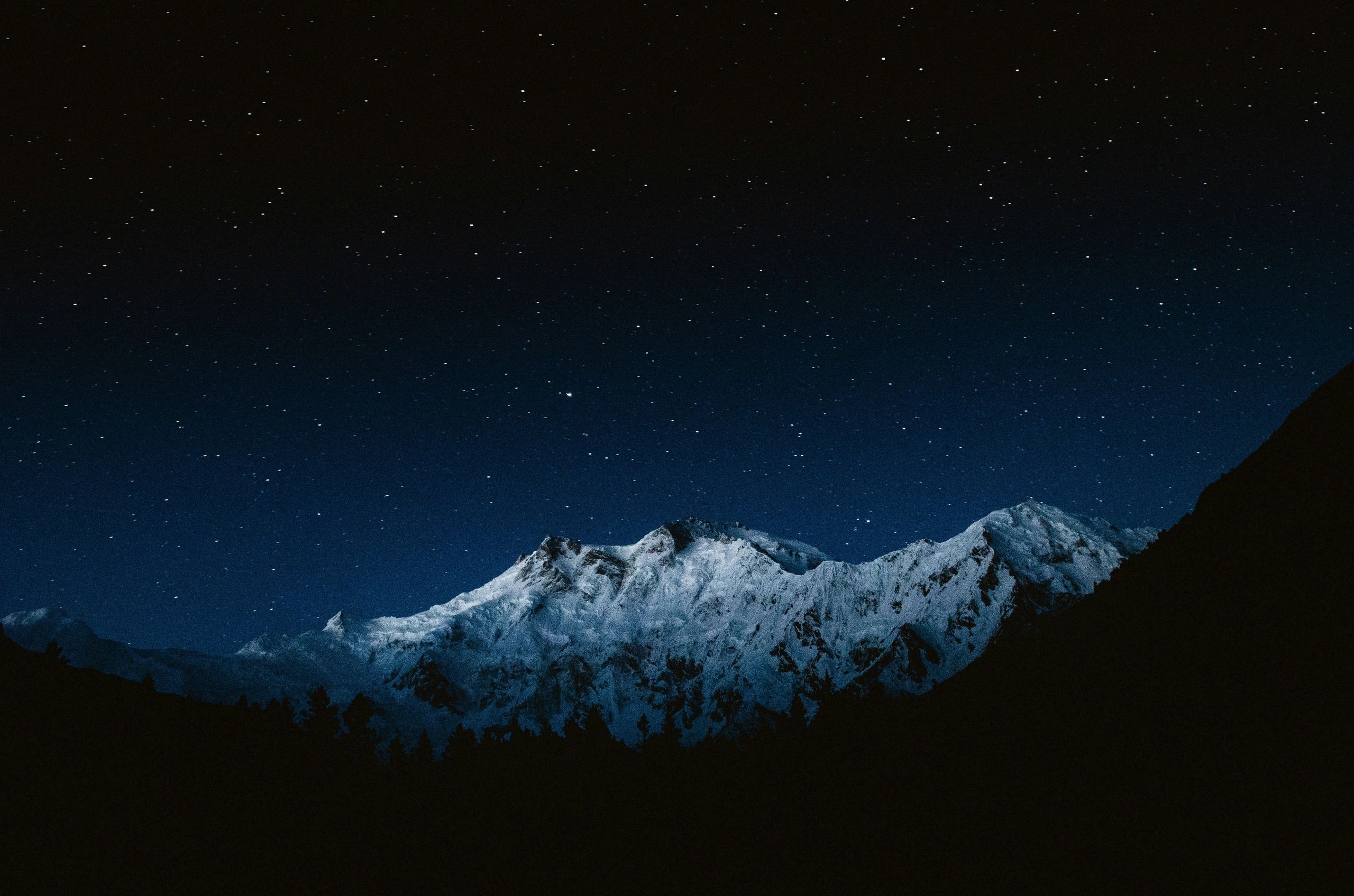 Snow-covered mountain peaks under a starry night sky.