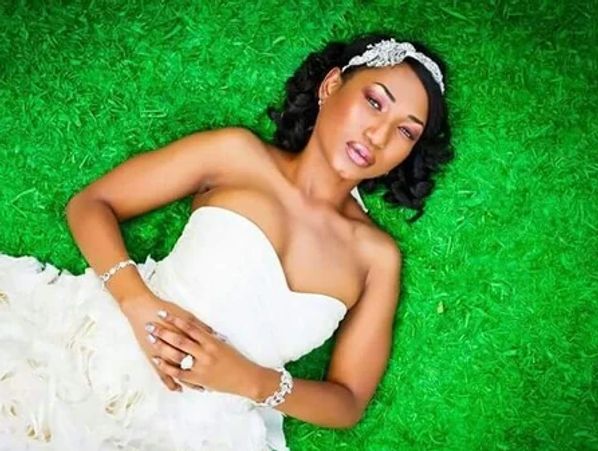 A bride in a wedding dress laying on grass with hair and makeup by ChiBeauty studios
