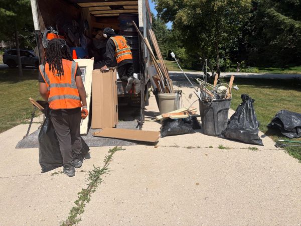 Two workers loading trash and debris into a truck.psjunkremovalwi.