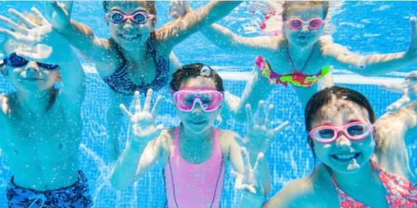 Kids wearing goggles having fun underwater in a swimming pool.