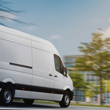 White delivery van driving fast on city street.
