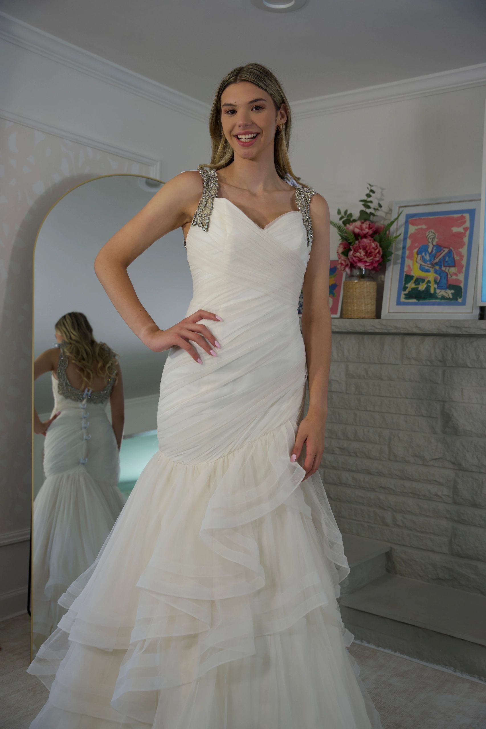 A woman in a white wedding dress smiling indoors.