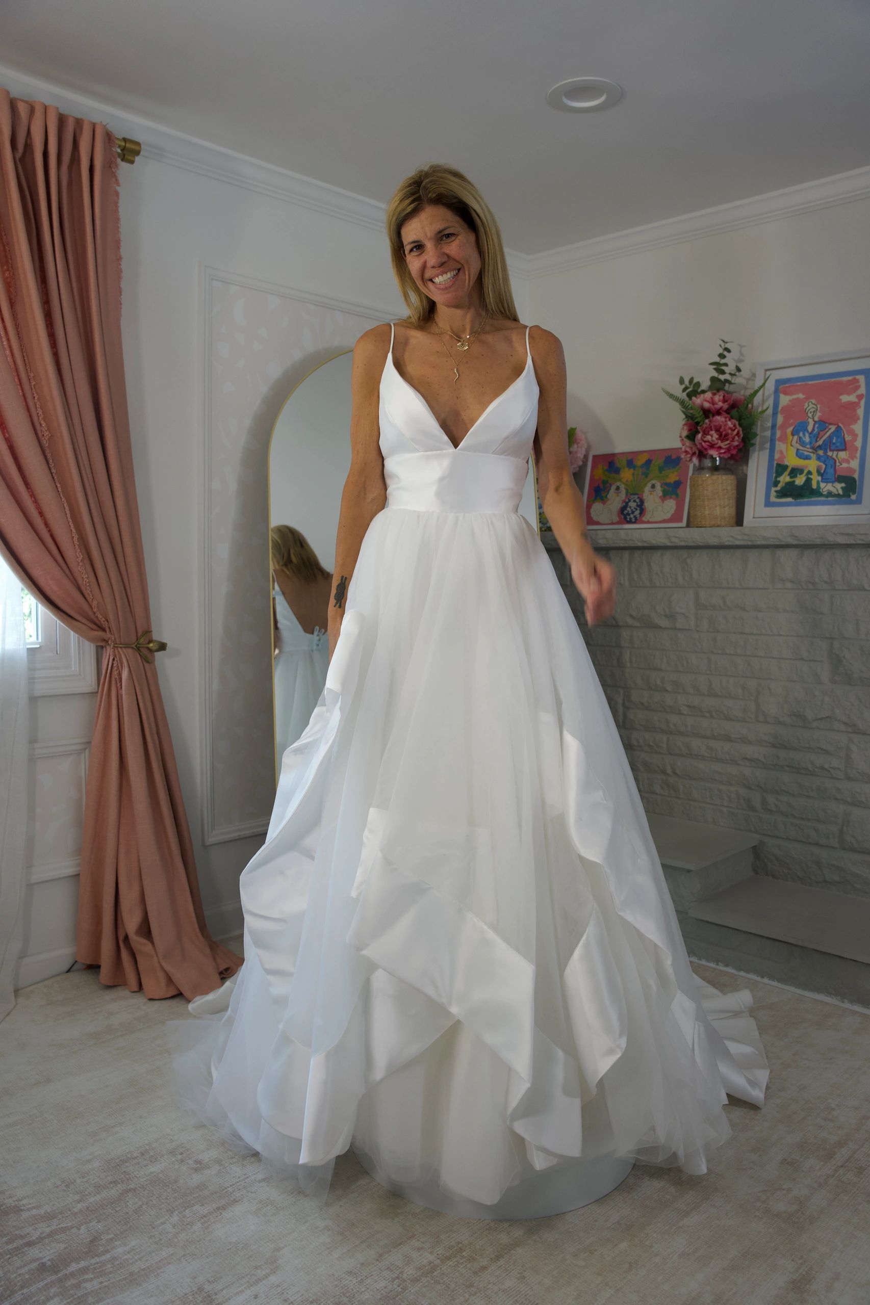 Woman in a flowing white gown smiling indoors.