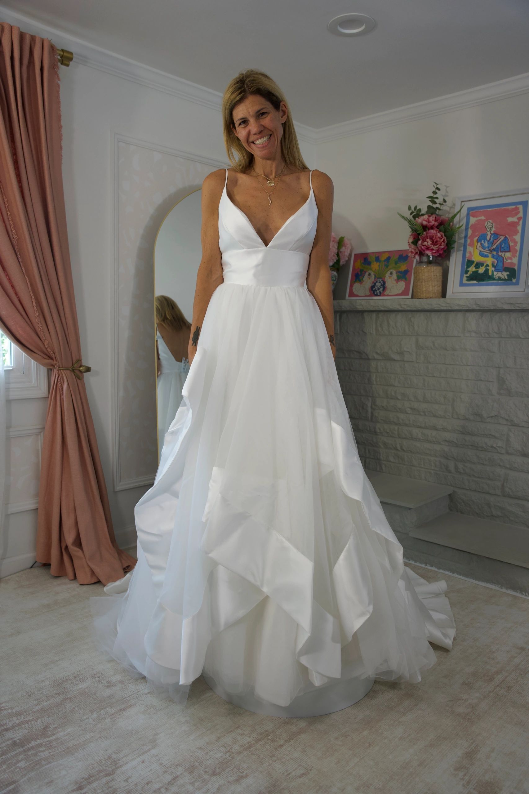 Woman in a white wedding dress smiling indoors.