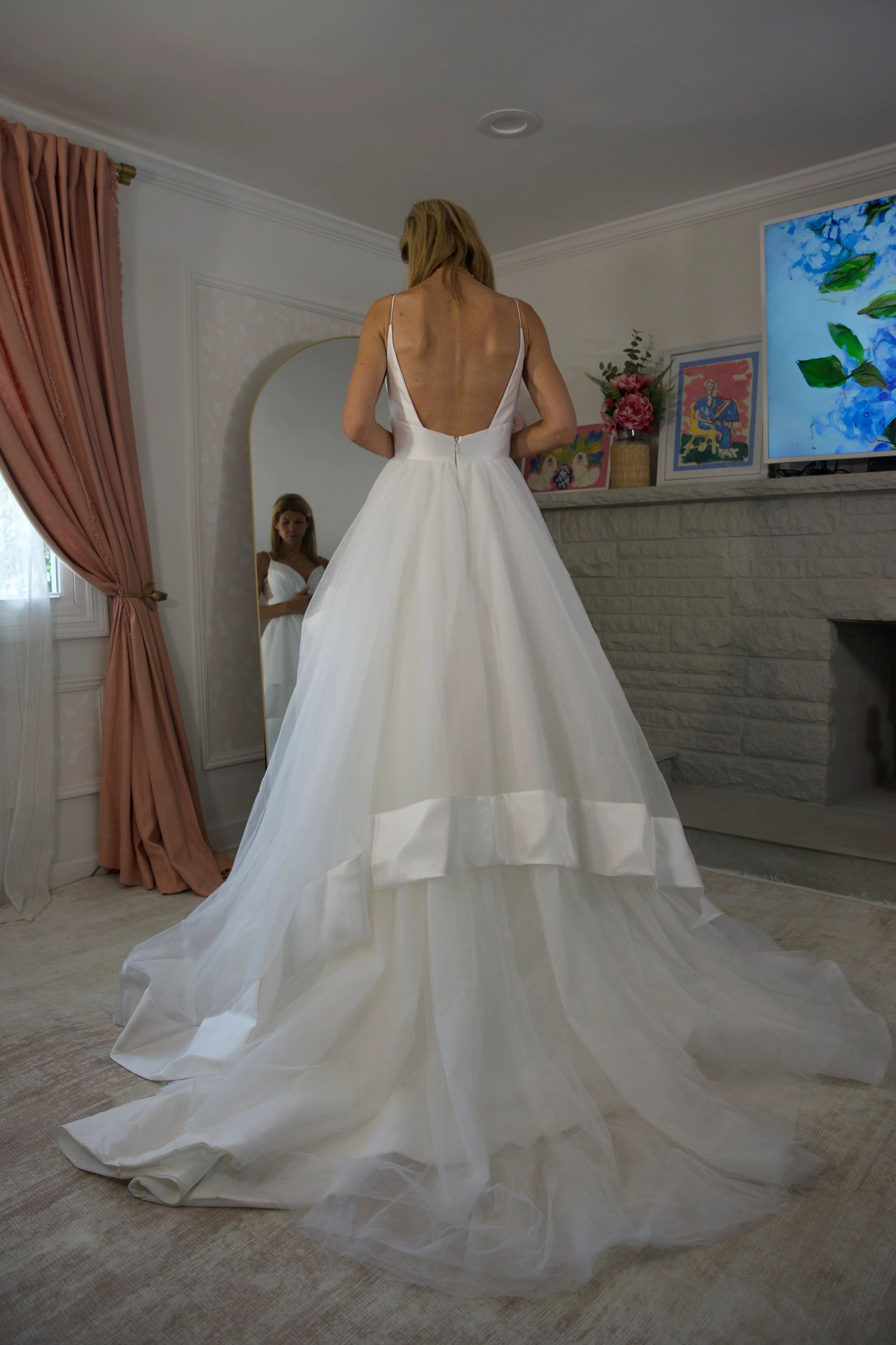Bride in a long white dress facing away in a room.